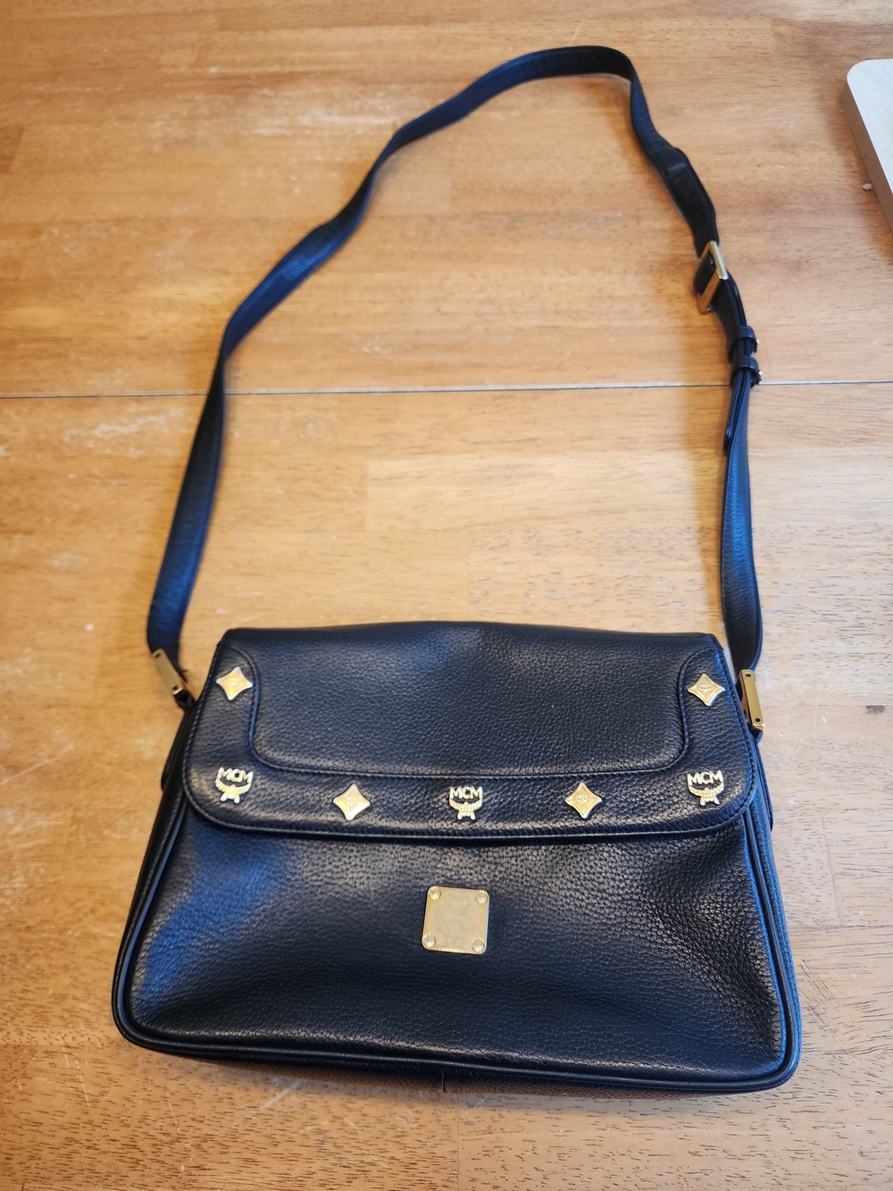 vintage MCM black leather crossbody bag  distinctive gold-toned logo studs